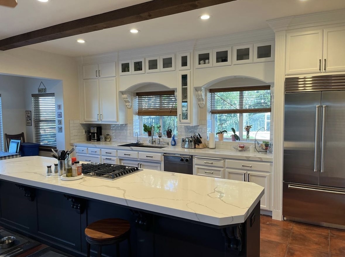 Refinished white kitchen cabinets with a navy island and quartz countertop